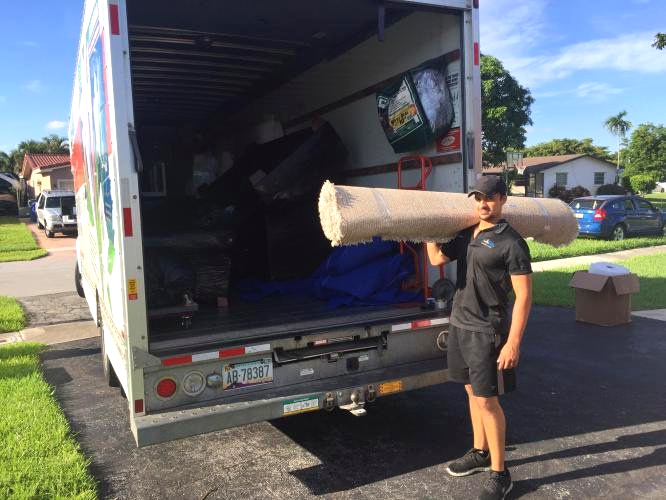 Movingtopia mover carrying a rug beside the truck